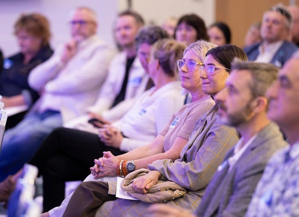 Business professionals listen to the speakers at the Thriving Through Change event.