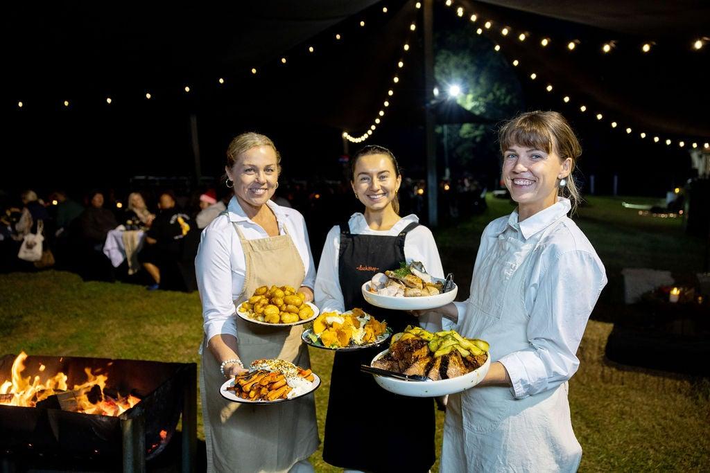 Three people holding plates to serve up at the Kenilworth Ember & Harvest Weekend event Wildfire & Wine