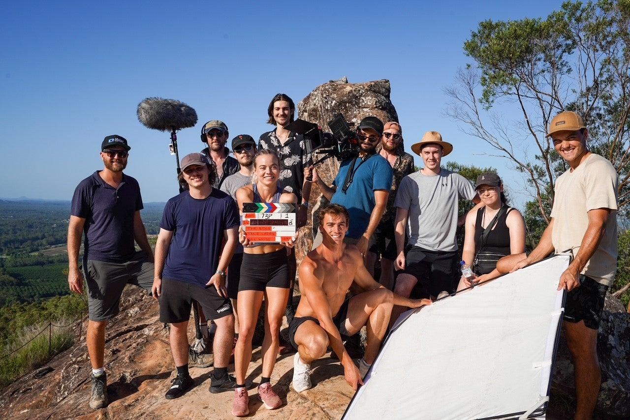 Ima ge of the film crew standing together with the actors with Sunshine Coast views back as a back drop.