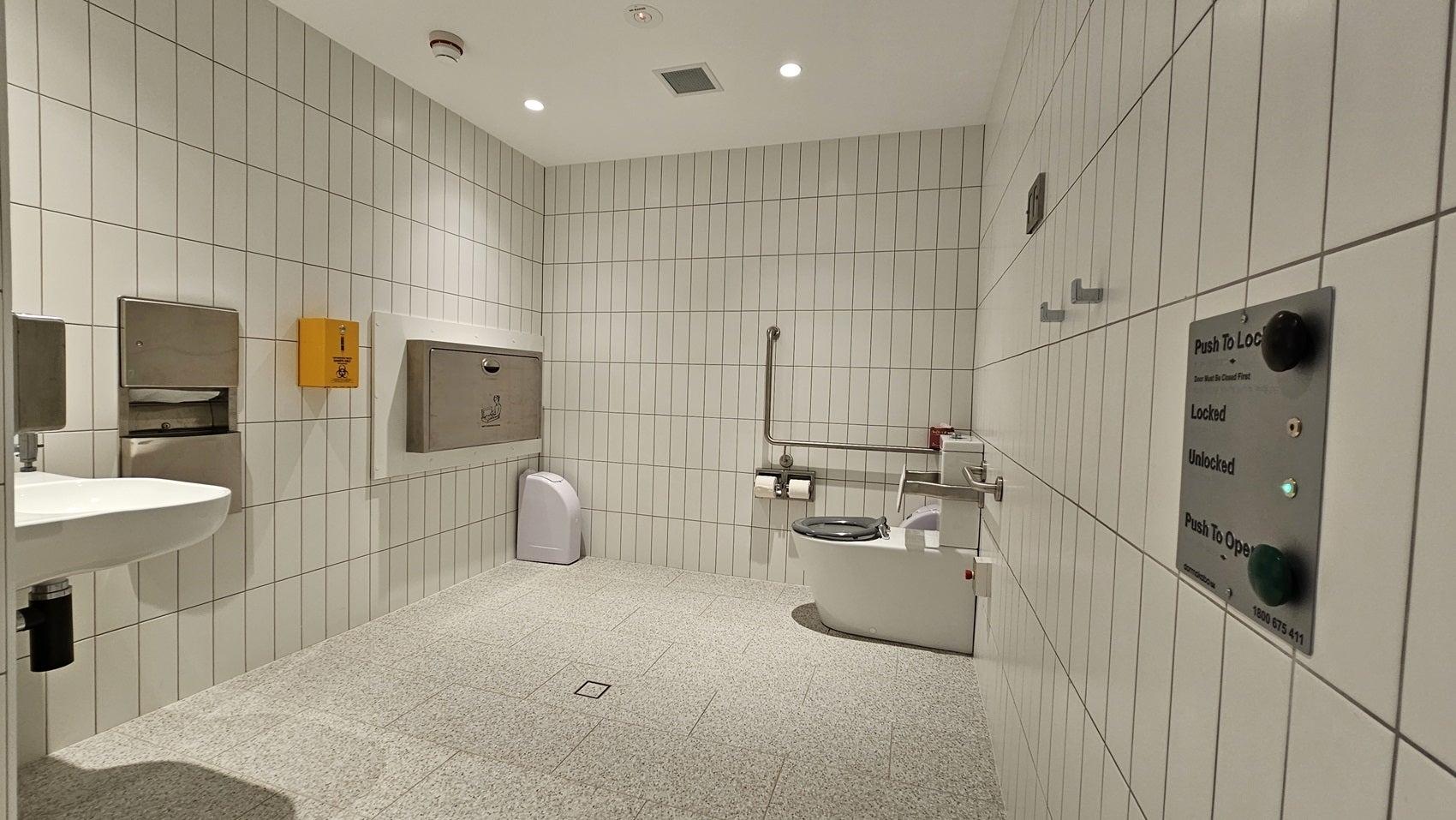 Altitude Nine amenities - toilet, sink, baby change station with signage and buttons on the wall for exit