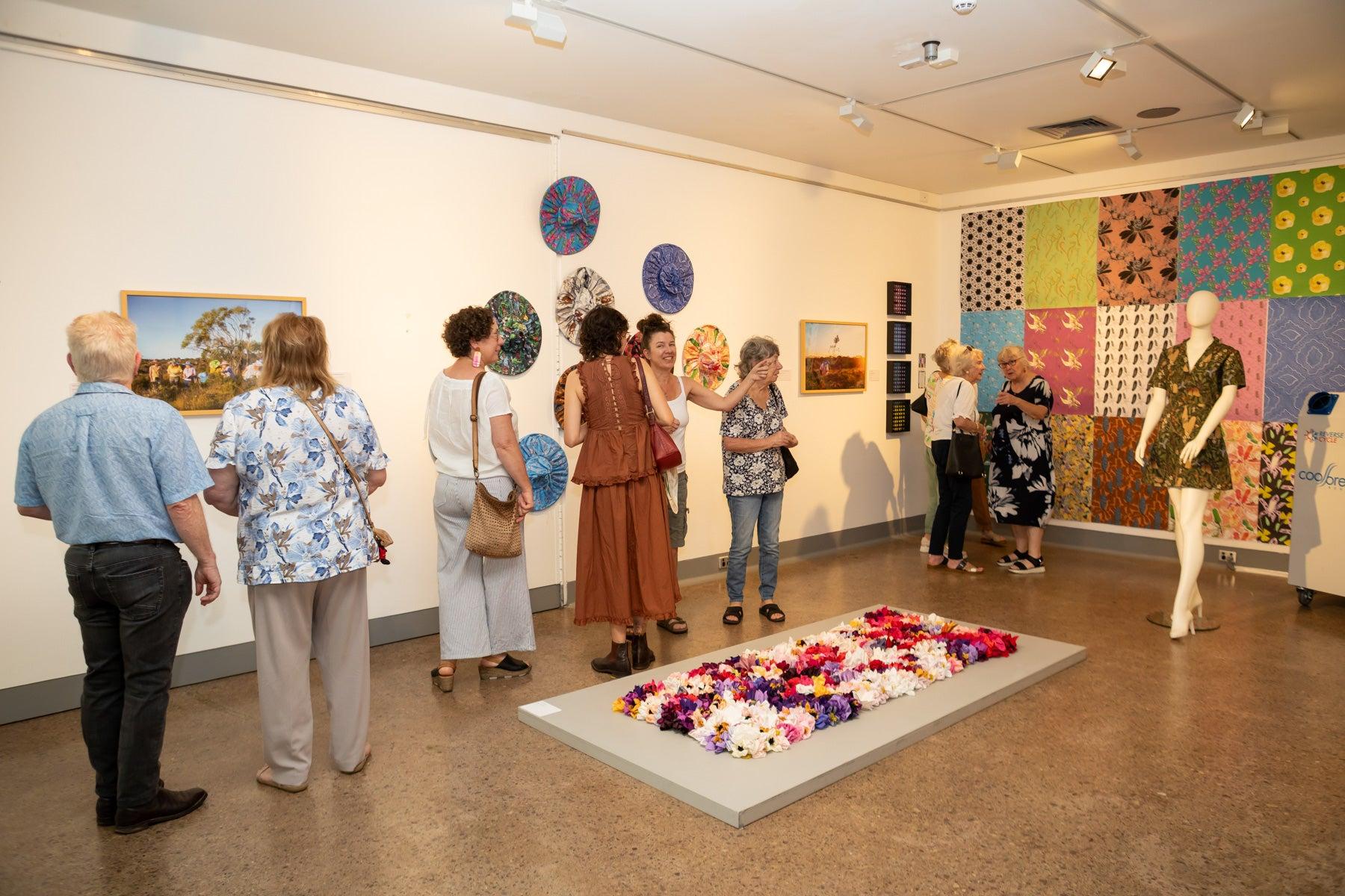 Crowds gather in the gallery surrounded by wildflower artworks