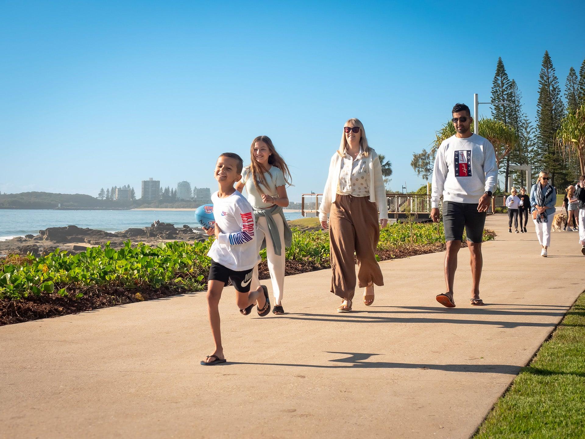 A family walking along a pedestrian pathway at Mooloolah foreshore park area