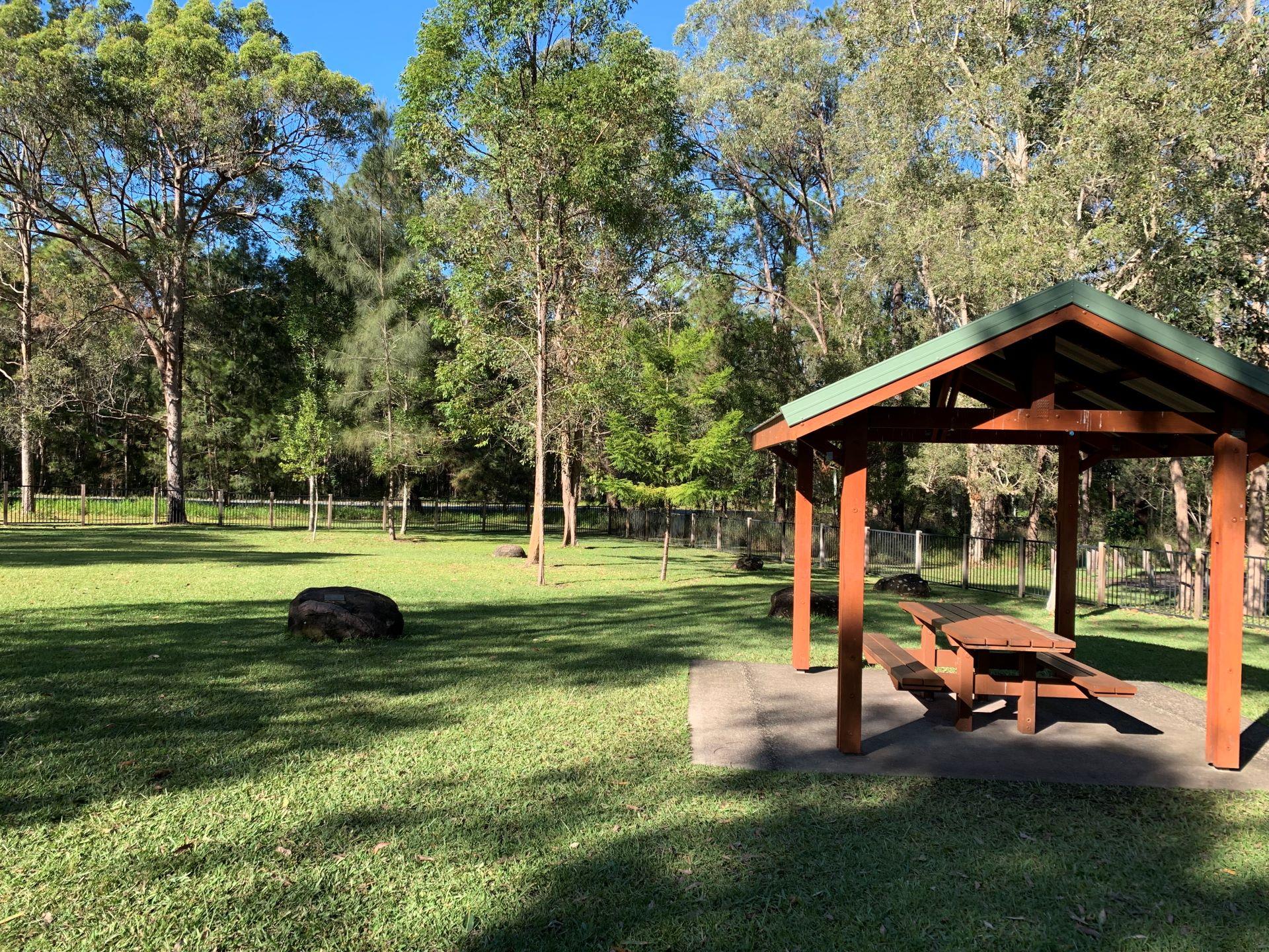 Fenced playground area with picnic tables and shelter