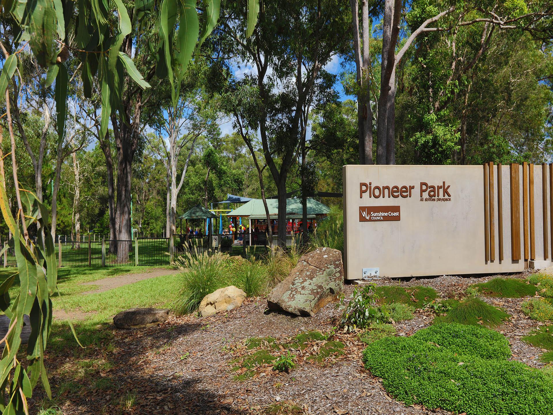 Playground sign, green grass and fenced area