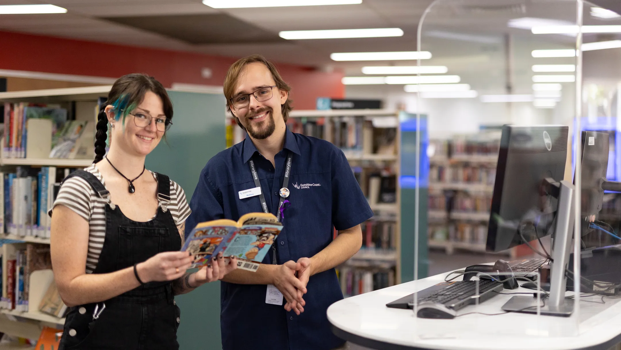 Library staff member helping member of the community with books
