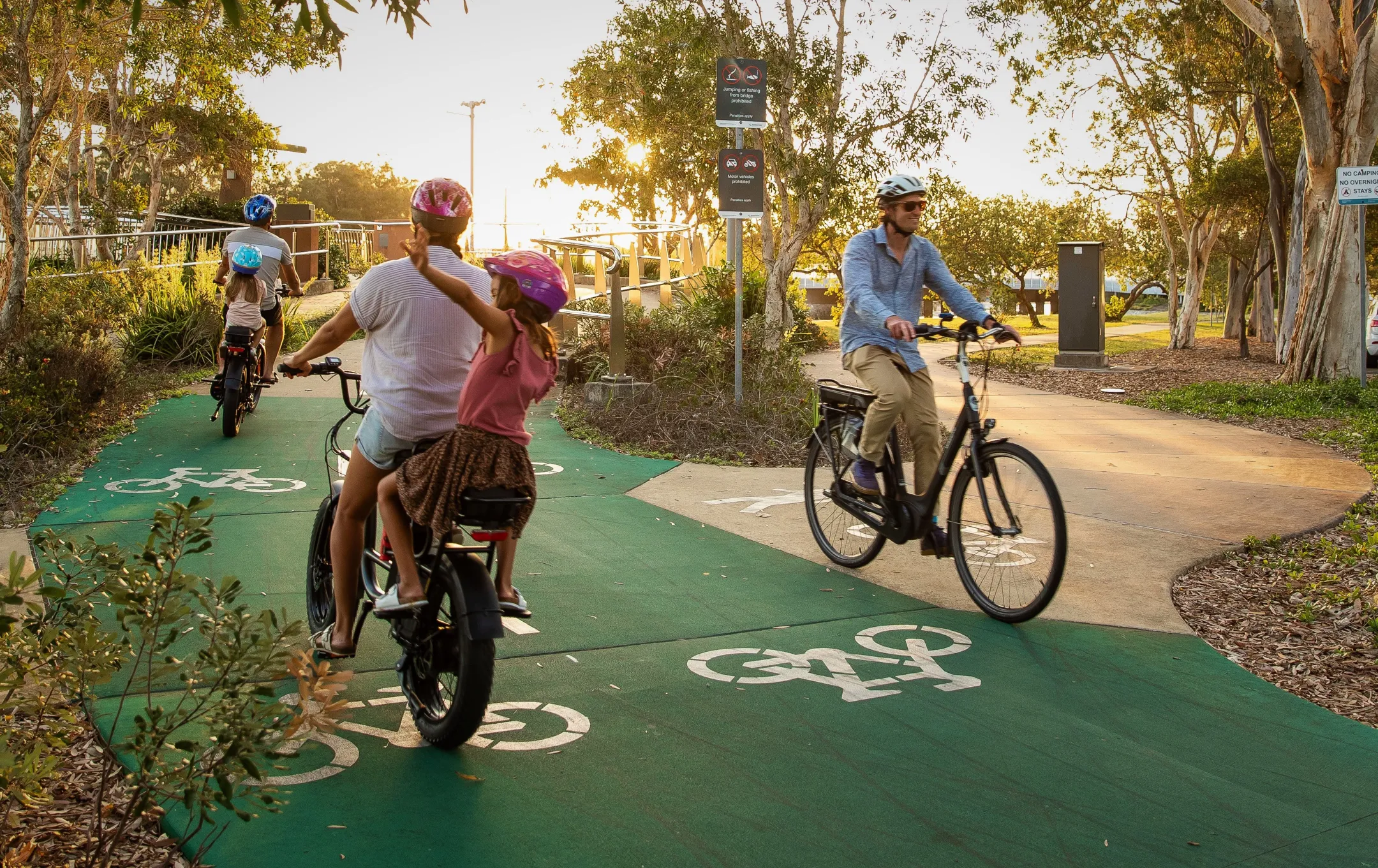 Bicycle riders going in both directions on a green bike path.