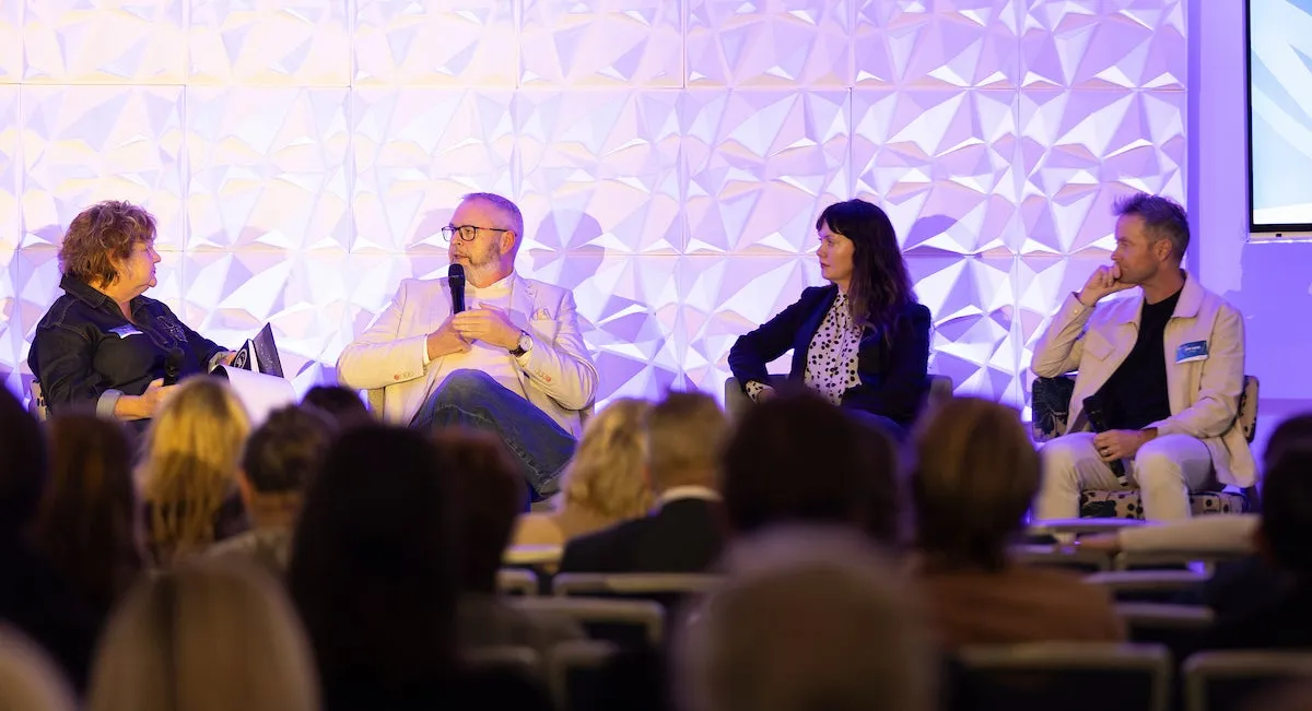 A panel of four people sit on a stage.
