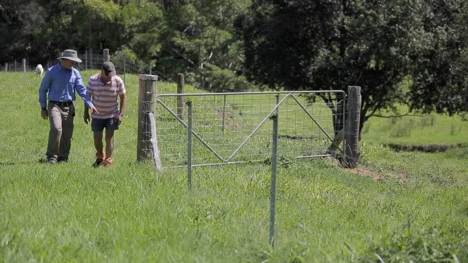 Council officer and farmer walking in a field near a access gate.