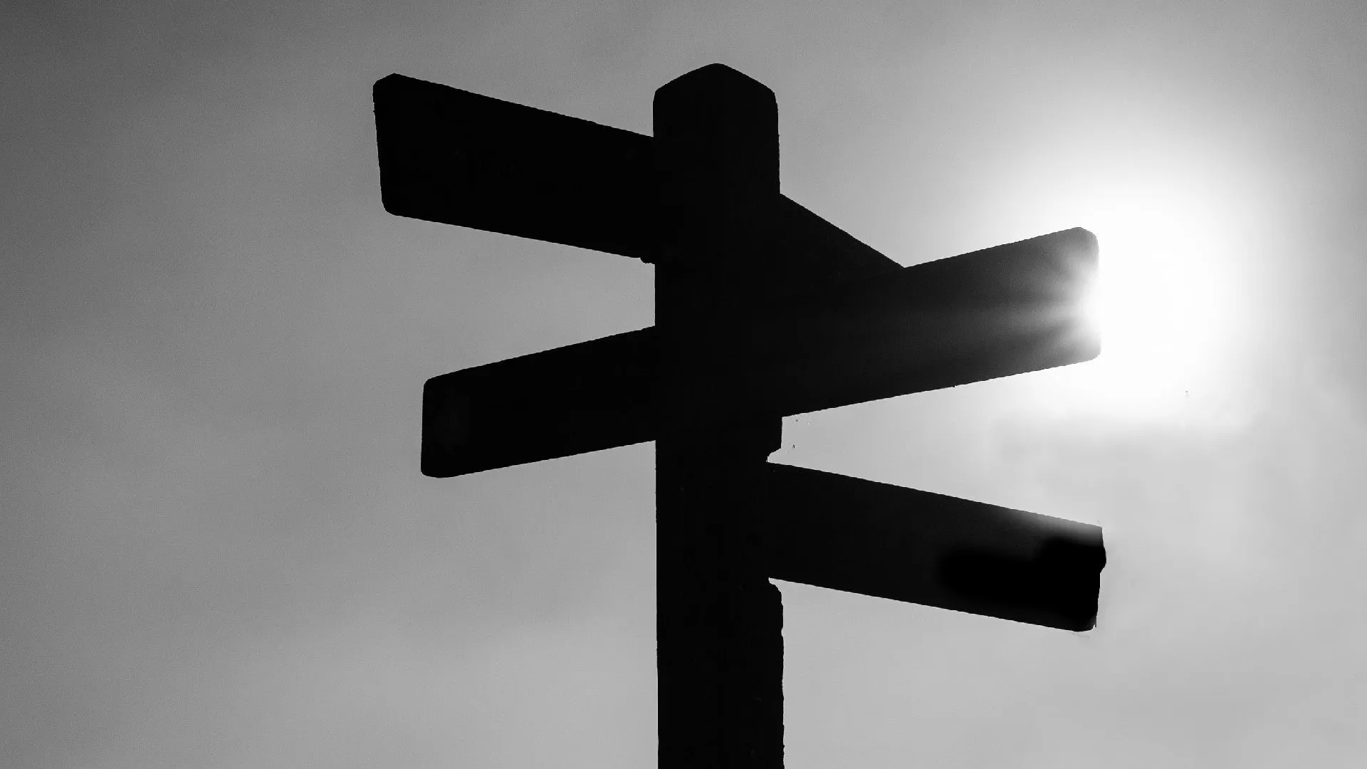 Silhouette of a road sign pointing in different directions.