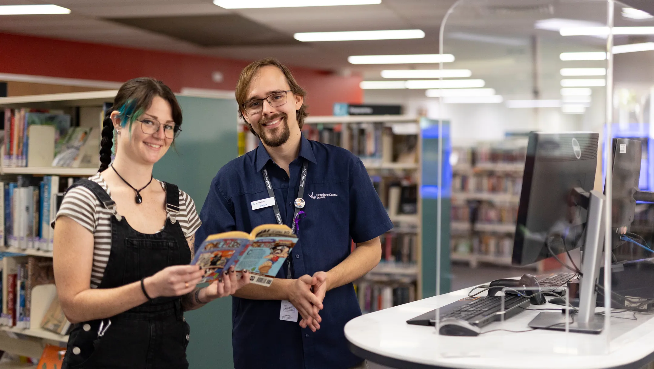 Library staff member helping member of the community with books