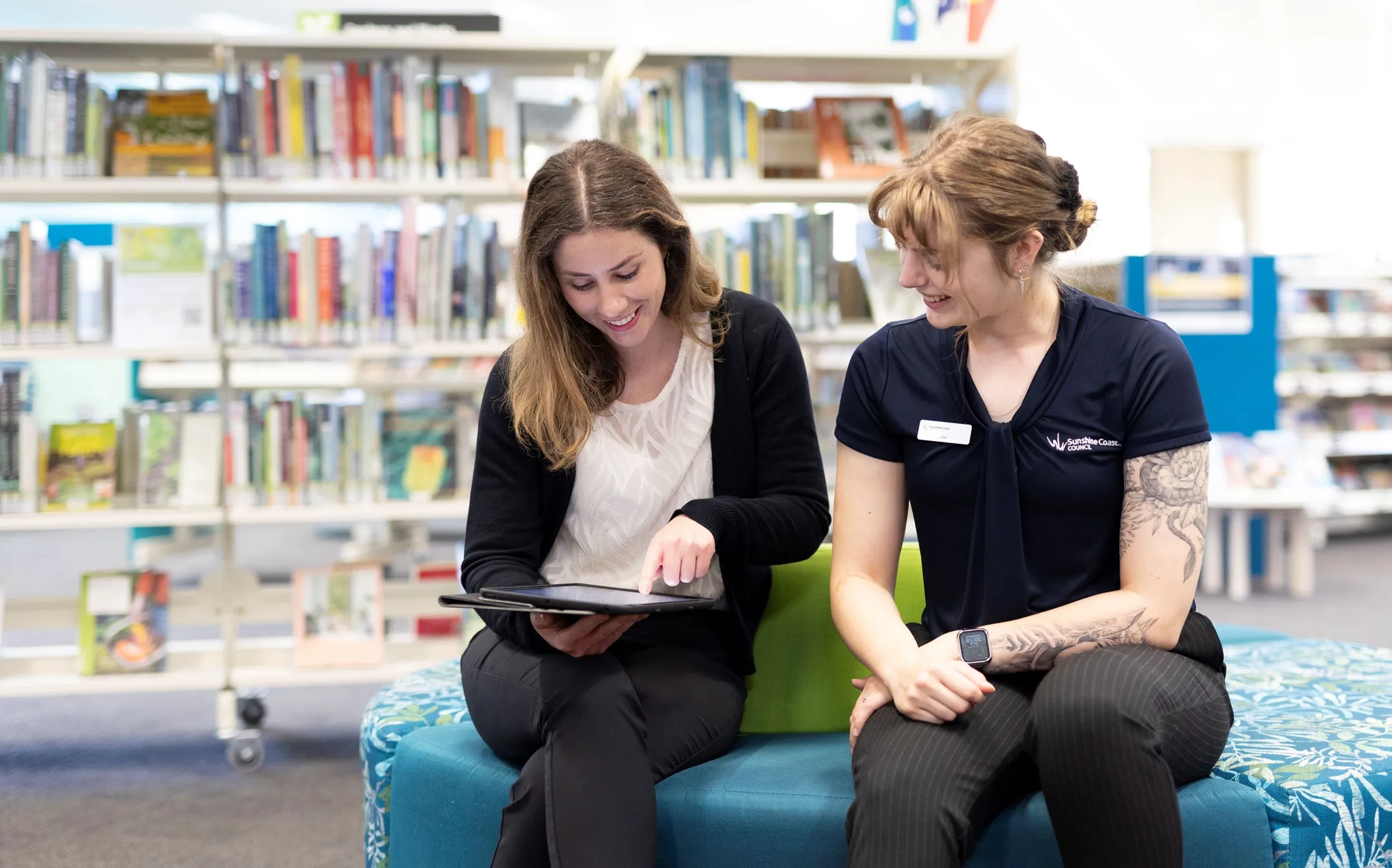 Library member using an iPad interacts with Library staff member in a Sunshine Coast Library.