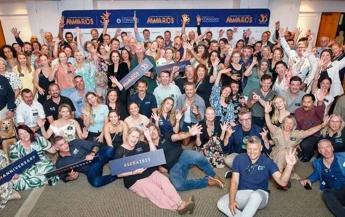 The 2026 finalists poised together as group - people holding various signs and others throwing their arms up in the air