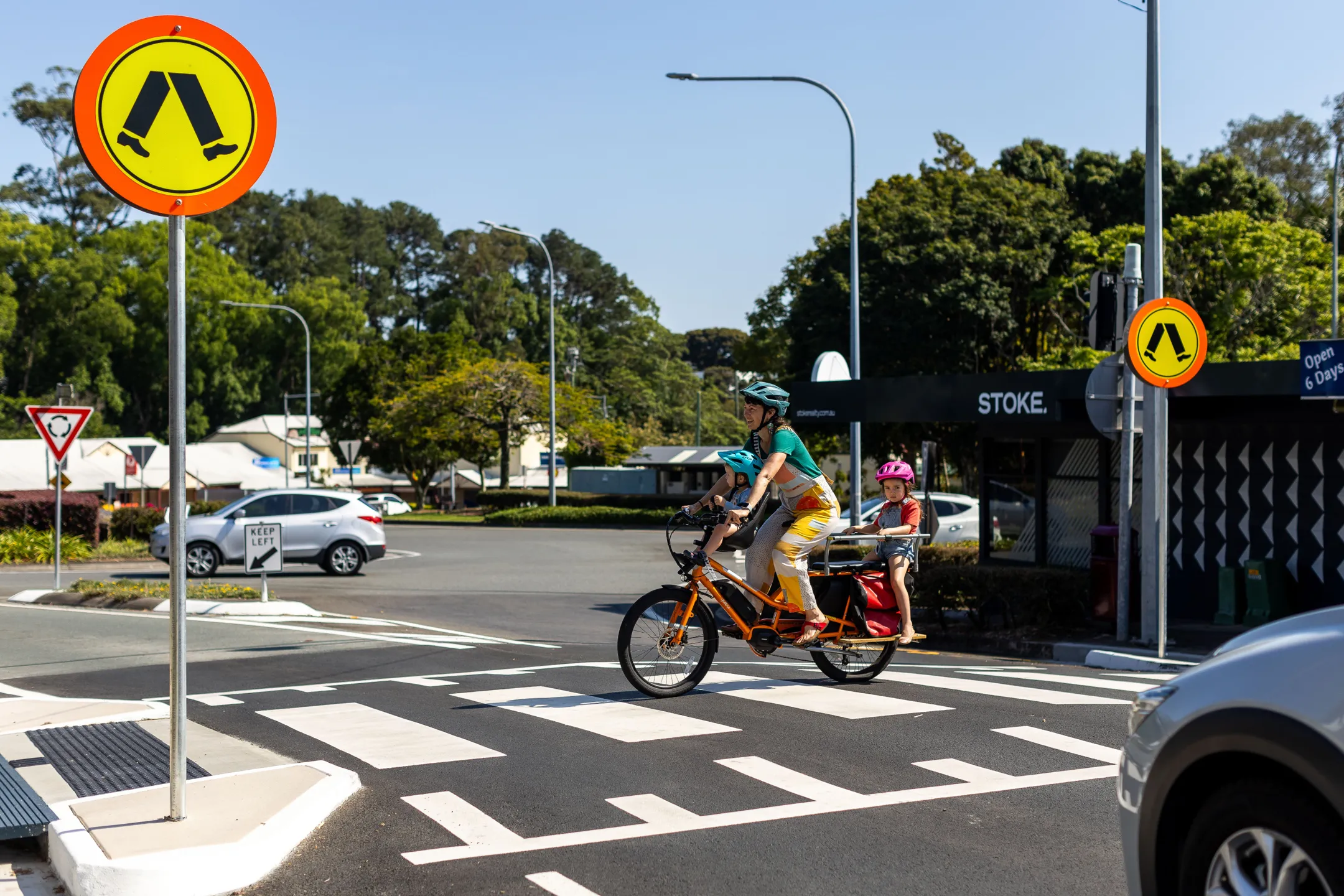 Mother and children on cargo e-bike crossing at a pedestrian crossing.
