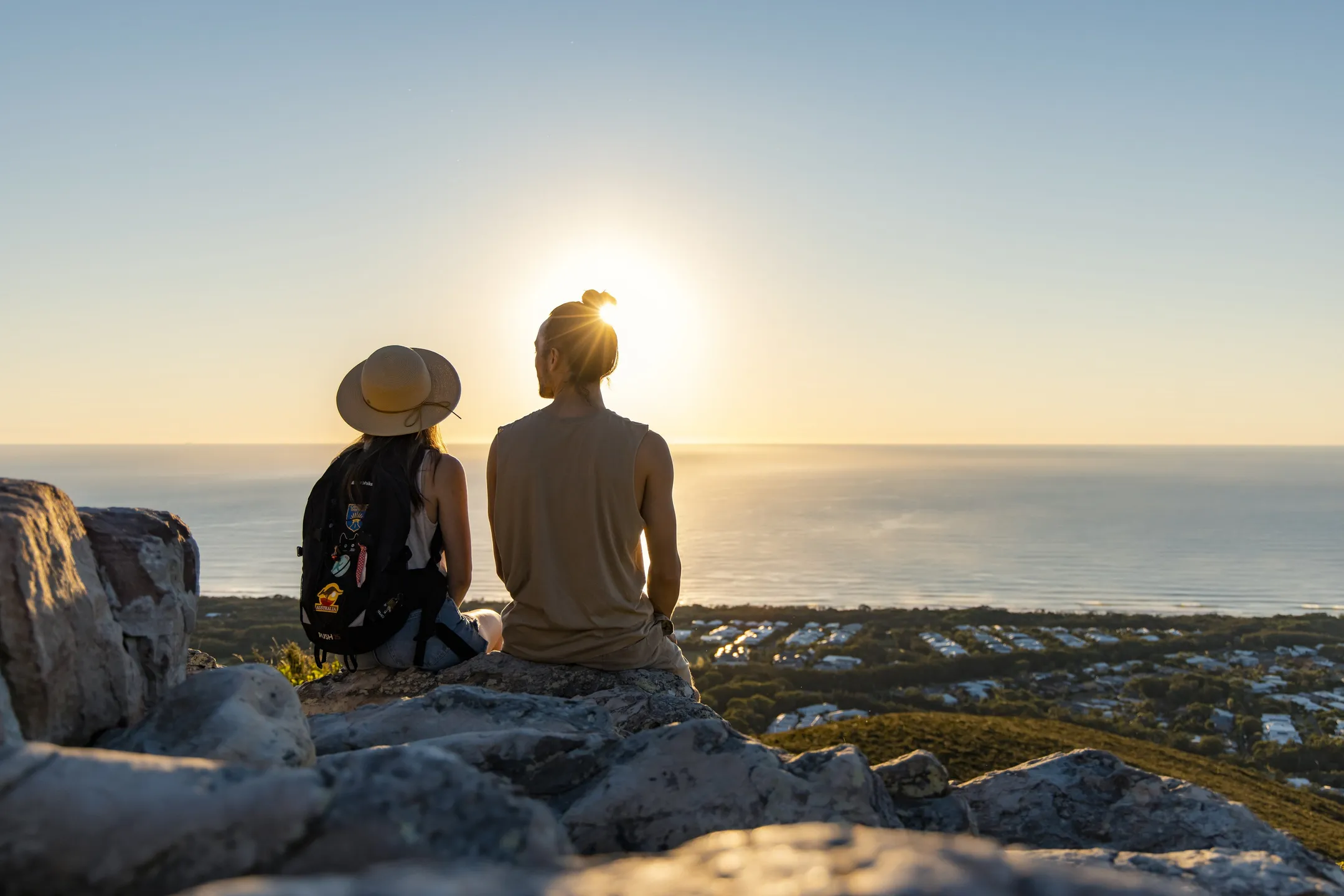 Two people sitting on top of Mount Coolum in the sunlight