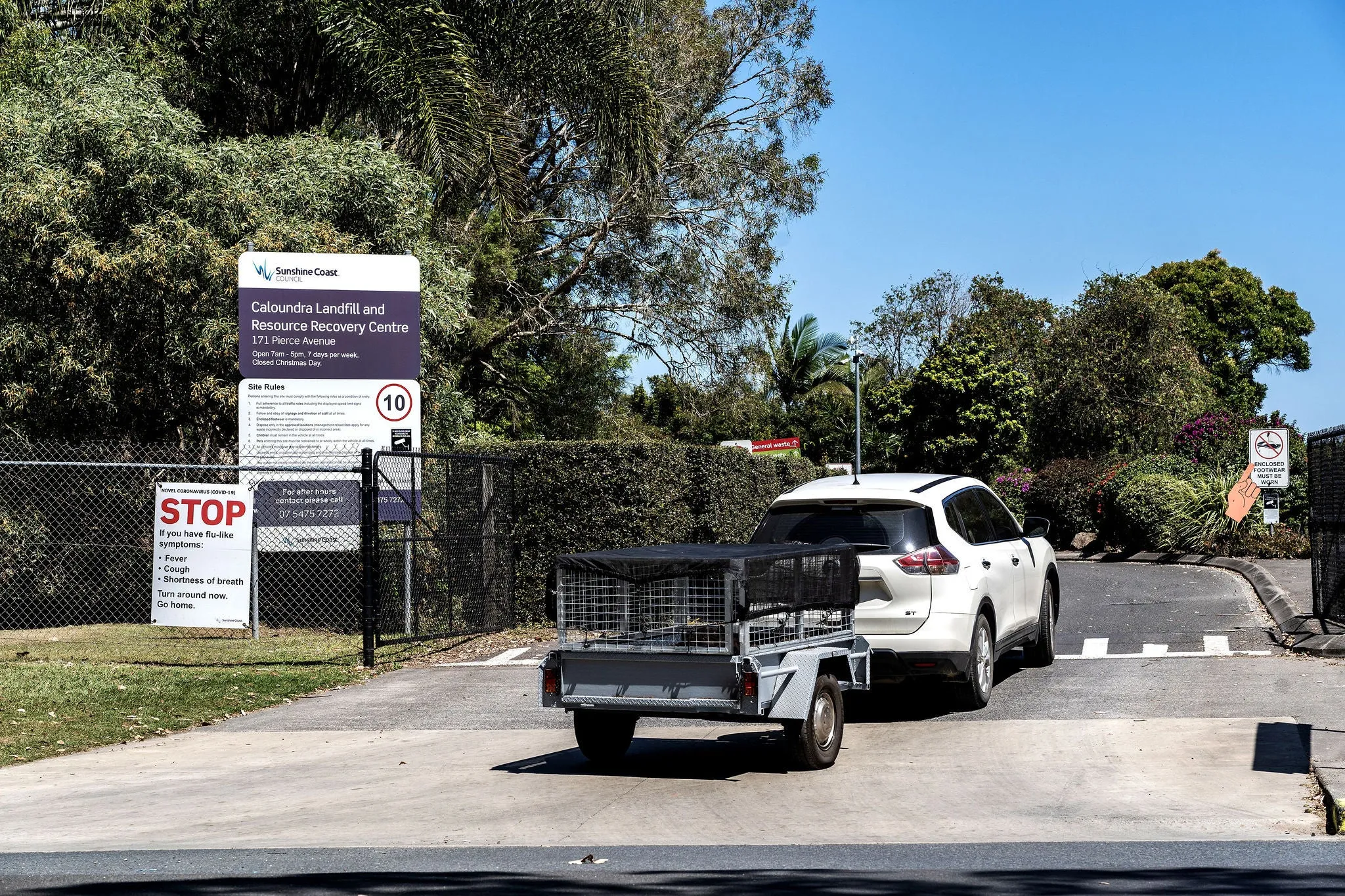 Car with trail driving into council dump.