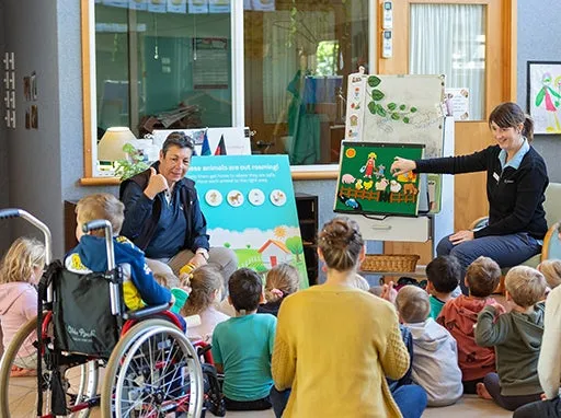 Pet education lesson in a classroom with children sitting on the classroom floor with one child in a wheelchair.