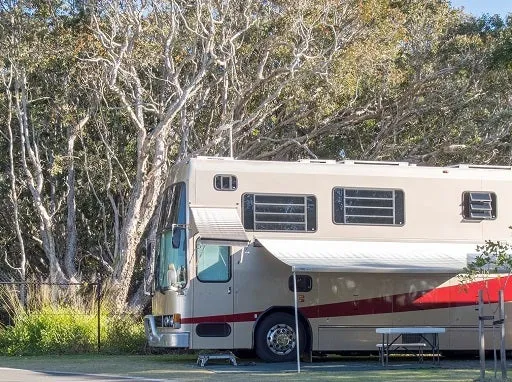A large RV parked and set up, complete with an awning and table.