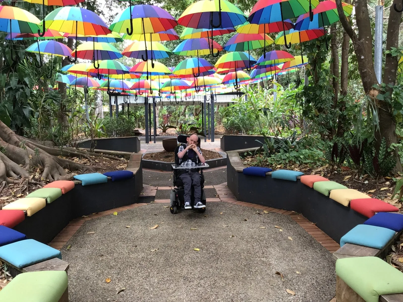 Person in wheelchair under umbrella installation at the Ginger Factory