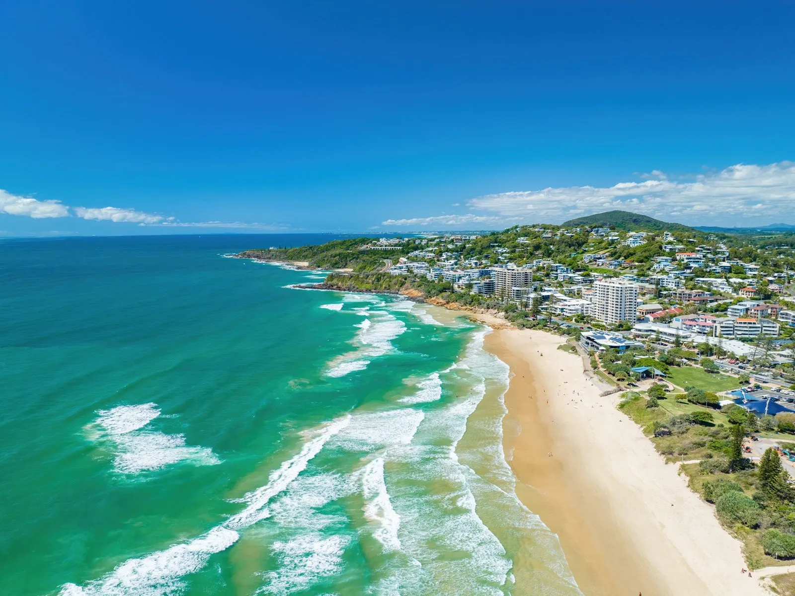 Aerial view of Coolum Beach showing the ocean and the town, with Mount Coolum in the distance