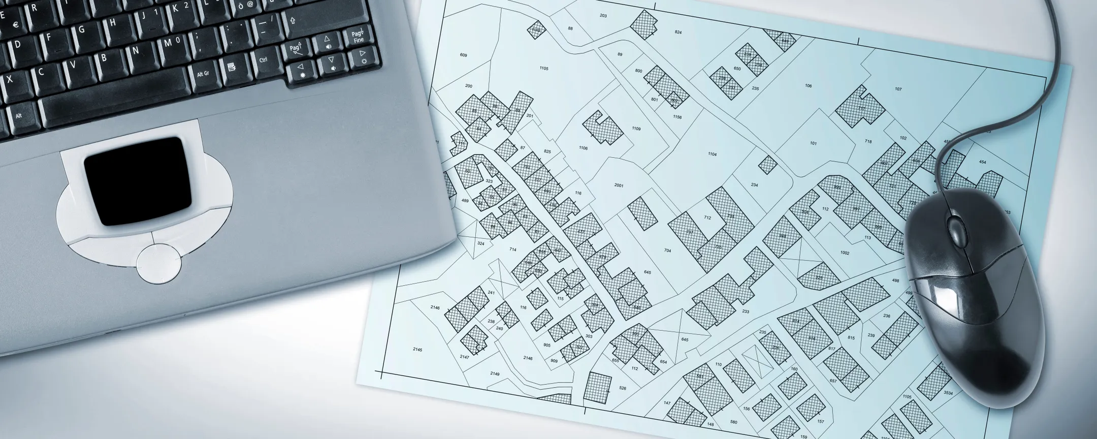 Laptop sitting on a table with a plan show blocks of land in a housing area.