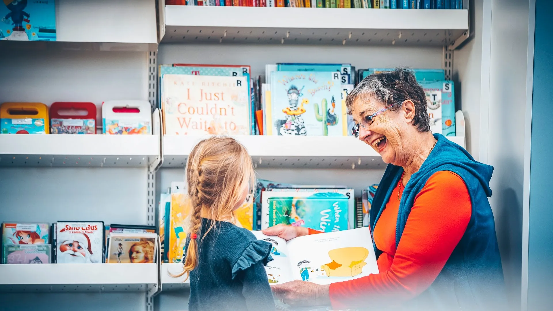 Lady in library reading a story to a young child.