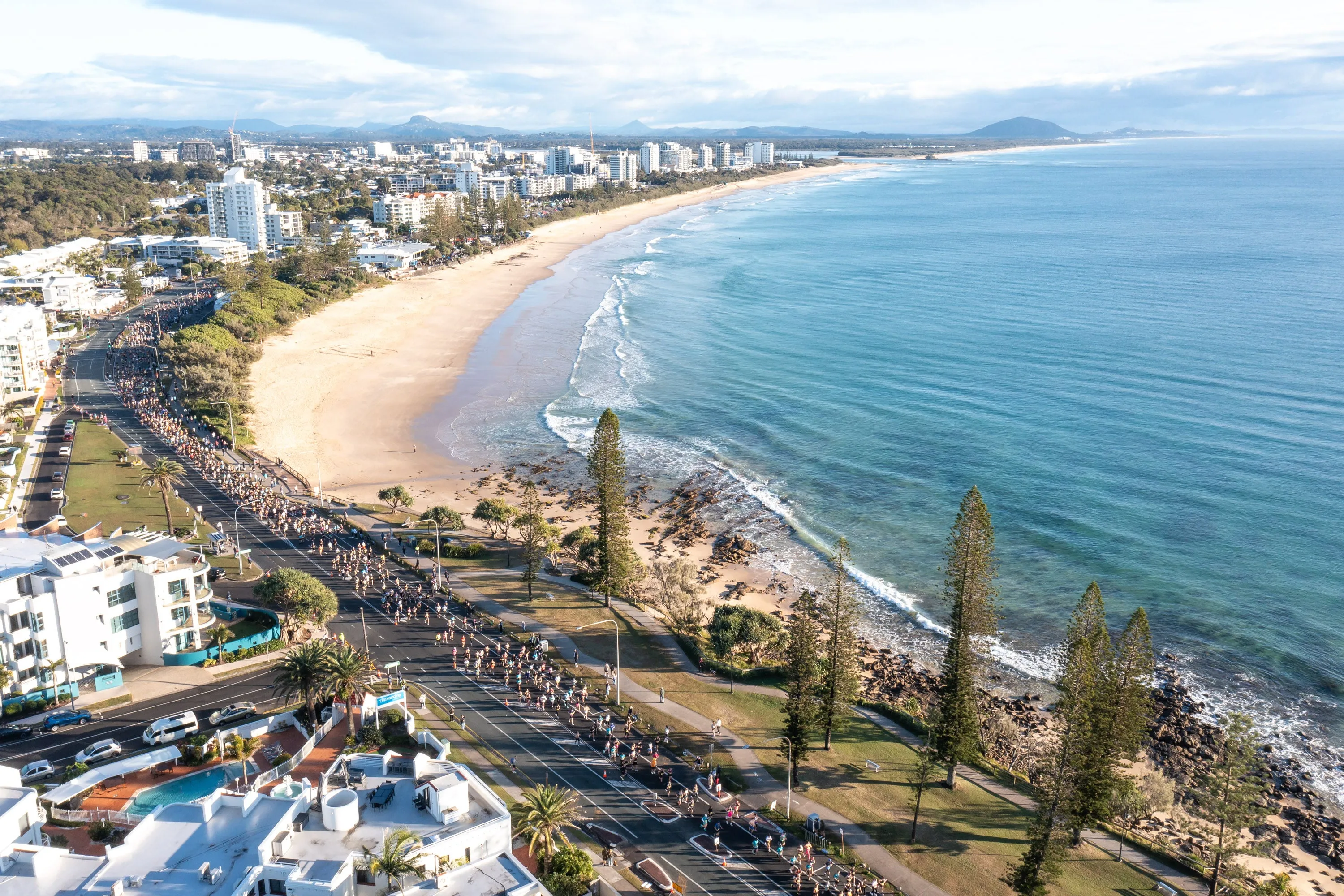 A drone image looking down on thousands of runners on the road between Alexandra Headland and Mooloolaba - with sweeping beach view behind them.
