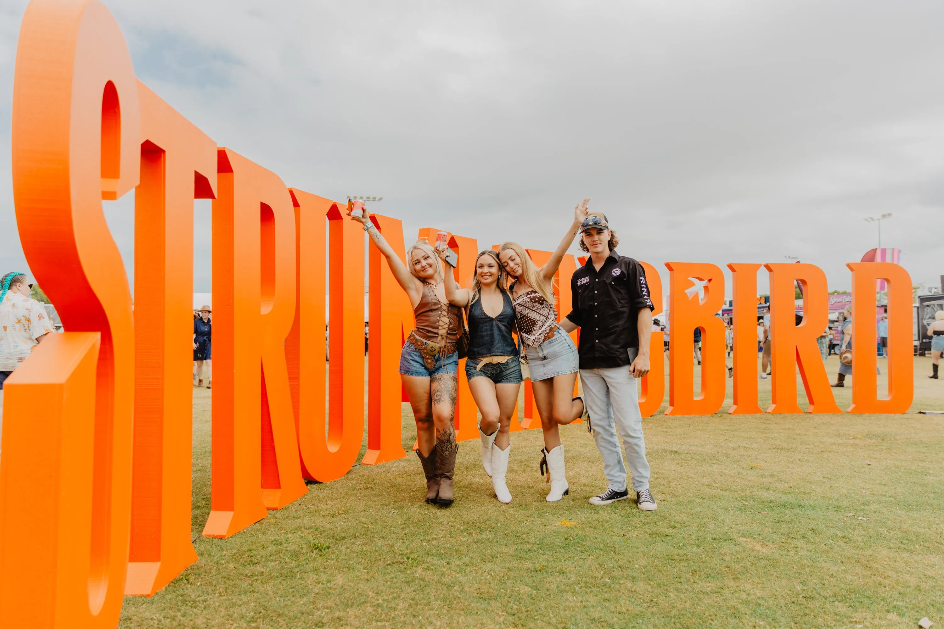The word Strummingbird spelt out in people height letters with four young people in front