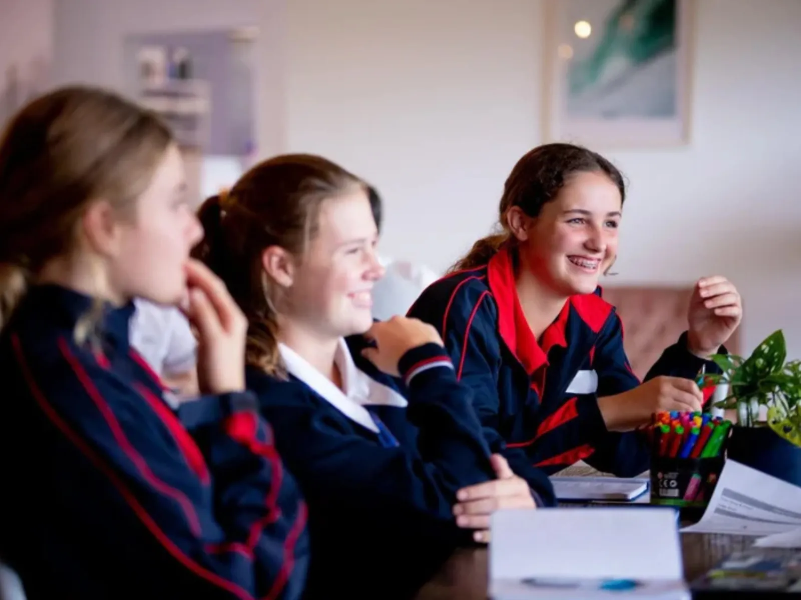 Mayor's Telstra Innovation Masterclass Series is opent ot Sunshine Coast studentes in Years 8-10. Three girls in navy and red trim school uniforms laughing and engaging in conversation.