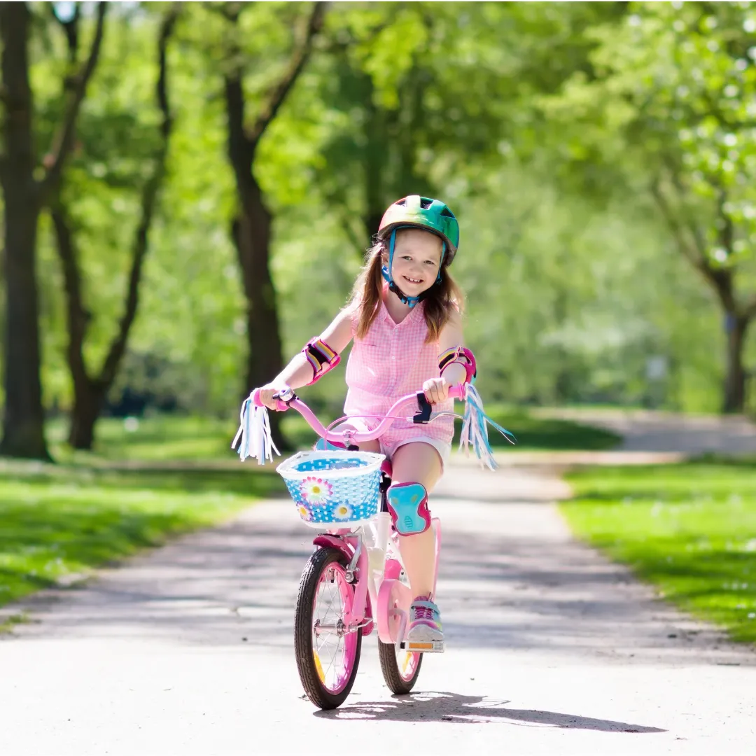 Girl on pink bike with basket and streamers.