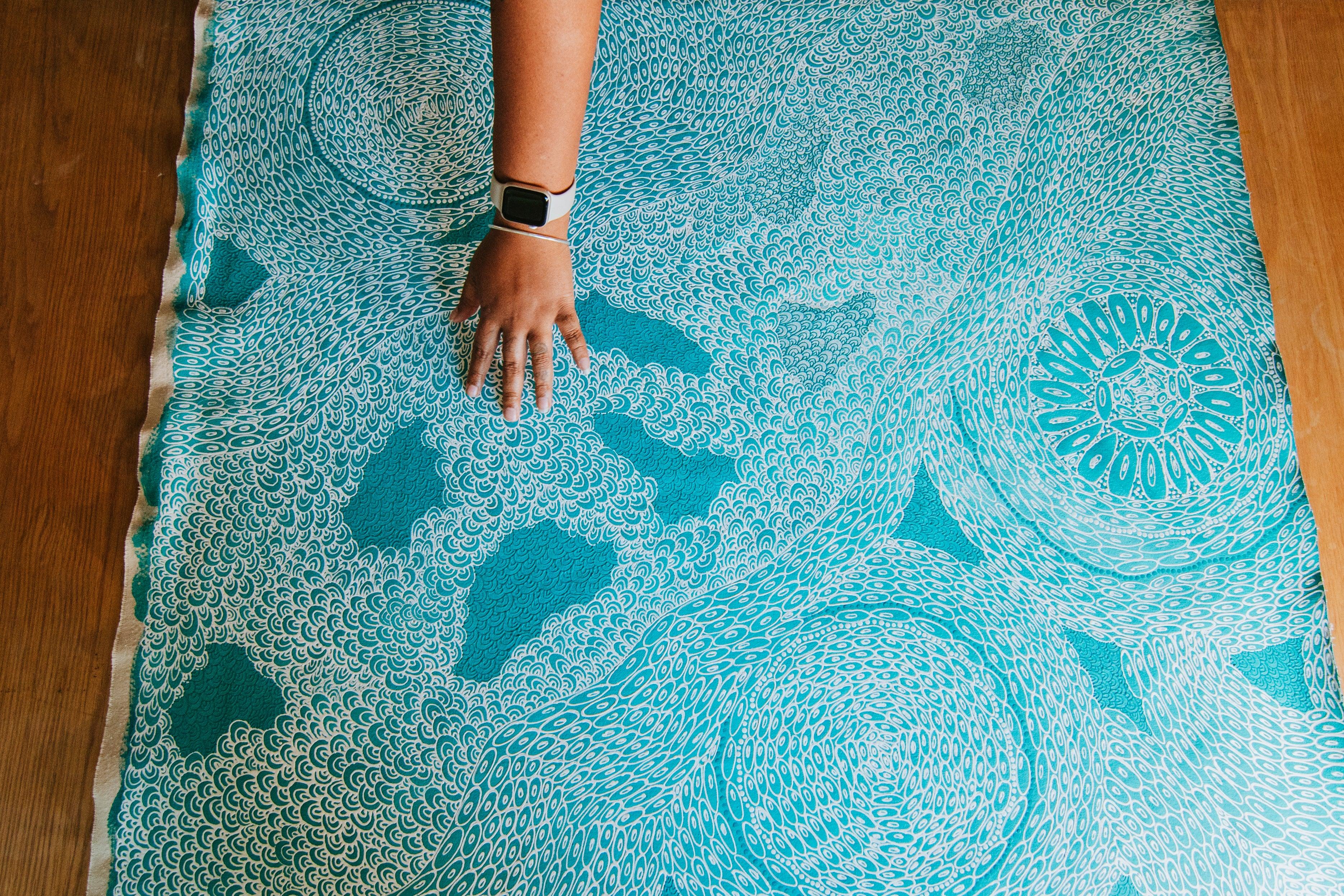 Project 24, artist Zartisha Davis. Image Cooper Brady Photography - Artwork laid out with a hand touching it